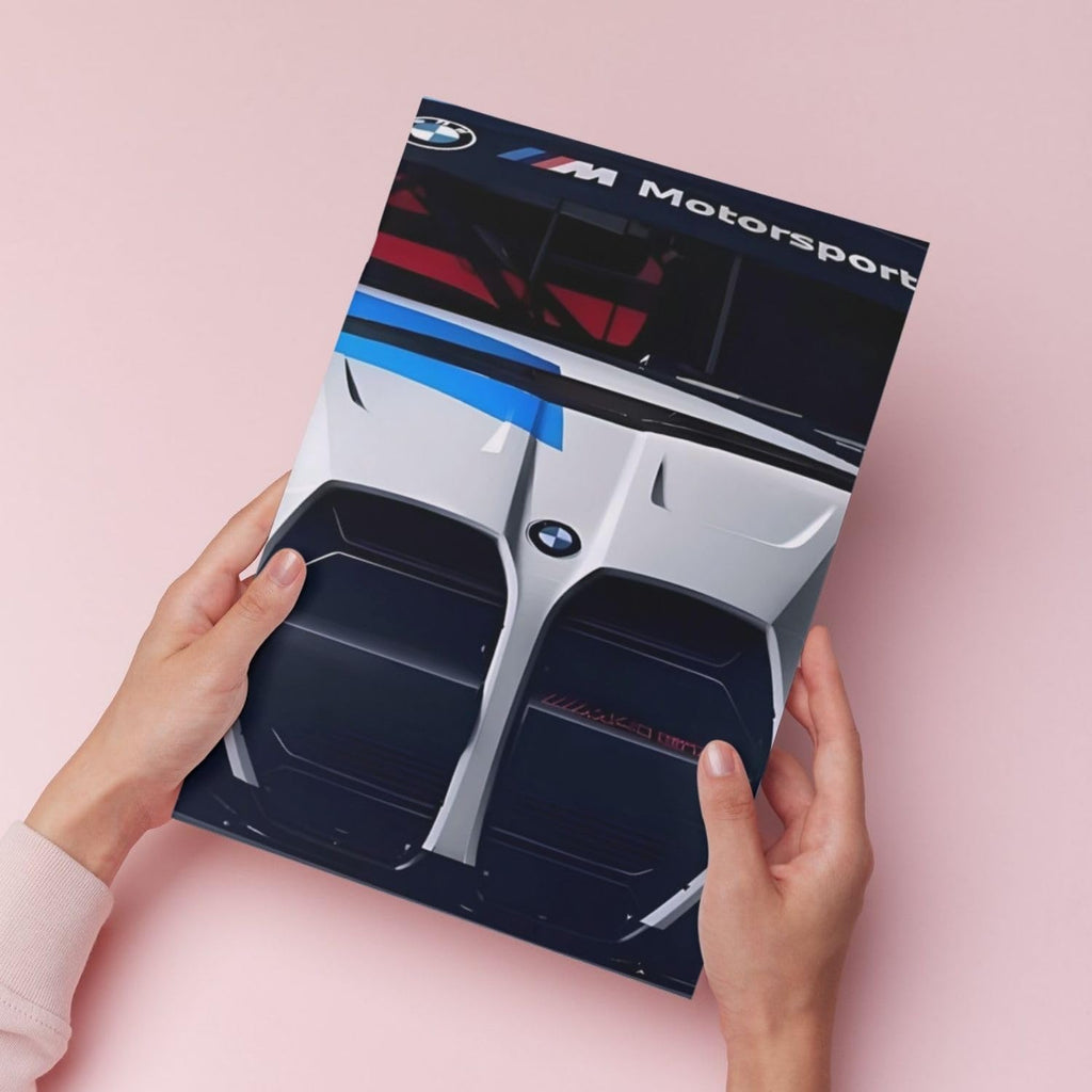 A person holds a printed poster featuring a close-up of a silver and black BMW Motorsport car front, against a soft pink background.