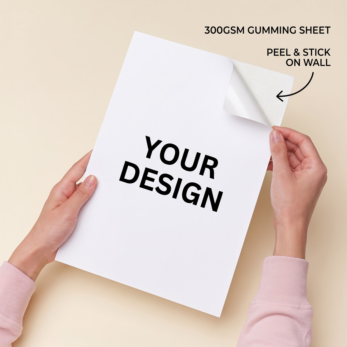 A person holds a white 300GSM gumming sheet with the text 'YOUR DESIGN' printed on it, peeling back the top-right corner to show the sticky backing. The background is a solid light beige, with text overlays reading '300GSM GUMMING SHEET' and 'PEEL & STICK ON WALL'.